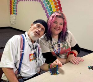 man with disabilities sittting at table smiling with caregiver