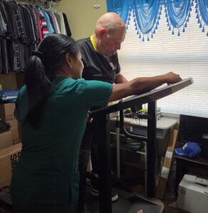 man with disabilities on treadmill helped by caregiver