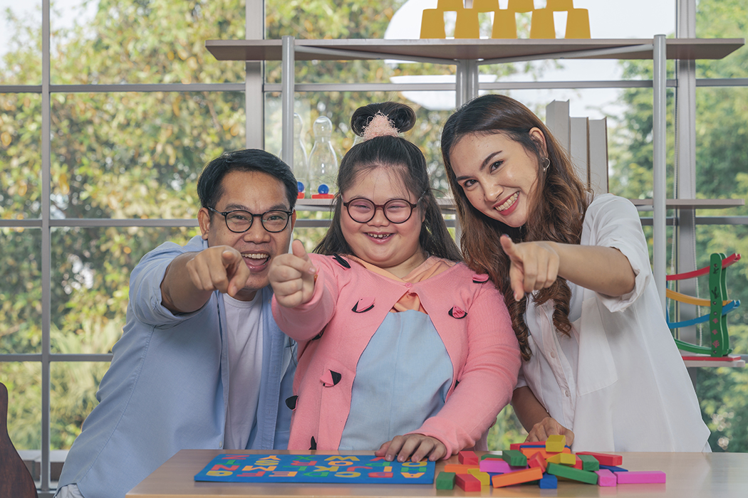 asian down syndrome teenage girl having fun playing education toy together with father and mother in game room at home